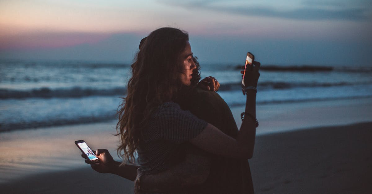 How do I connect with my friend that also has shaders? - Couple hugging and using smartphone near sea on sunset