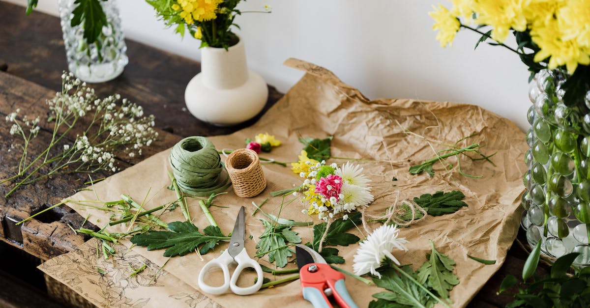 How do I create a glass pane roof? - Scissors and pruner on craft paper covered with cut leaves and flowers among bouquets on wooden table in floristry workshop