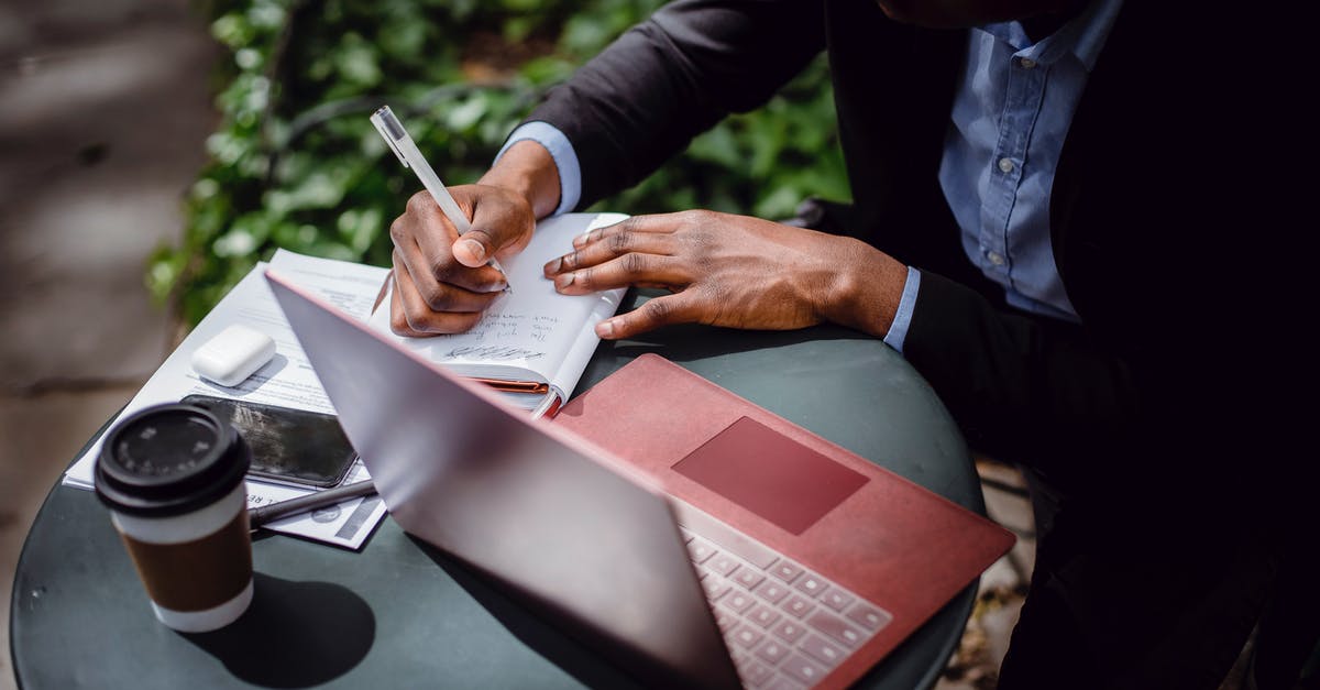How do I create a repeating charge using redstone/repeaters? - From above of crop black male journalist in formal wear writing article while sitting at table with red laptop and cup of takeaway coffee