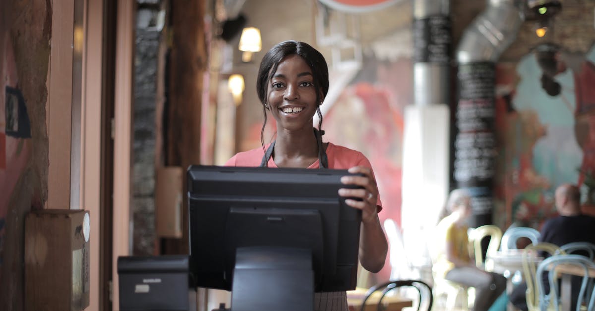 How do I delete a custom room? - Positive young woman in uniform smiling while standing at counter desk in  cafe