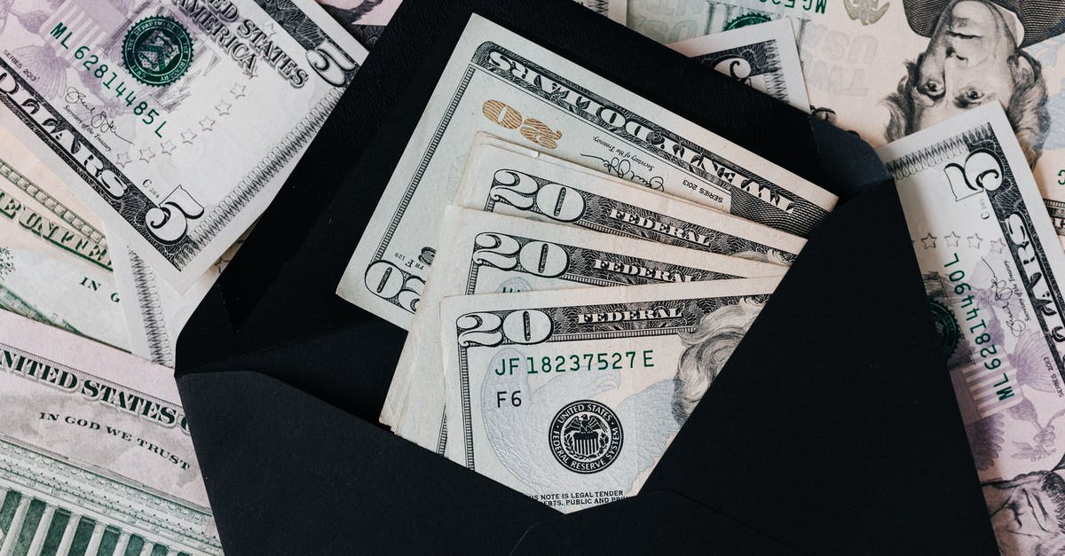 How do I earn credits? - From above of dollar bills in opened black envelope placed on stack of United states cash money as concept of personal income