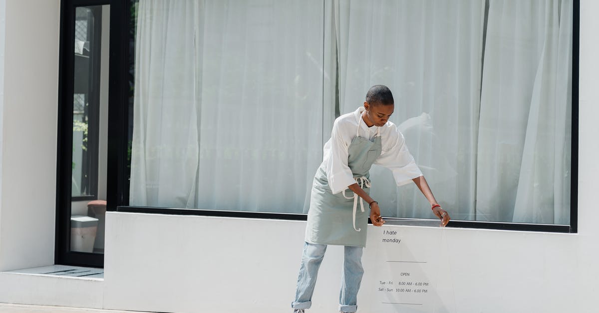 How do I find the secret, invisible house? - Diligent black female worker setting signboard outside cafeteria at sunny day How do I find the secret, invisible house? - Diligent black female worker setting signboard outside cafeteria at sunny day