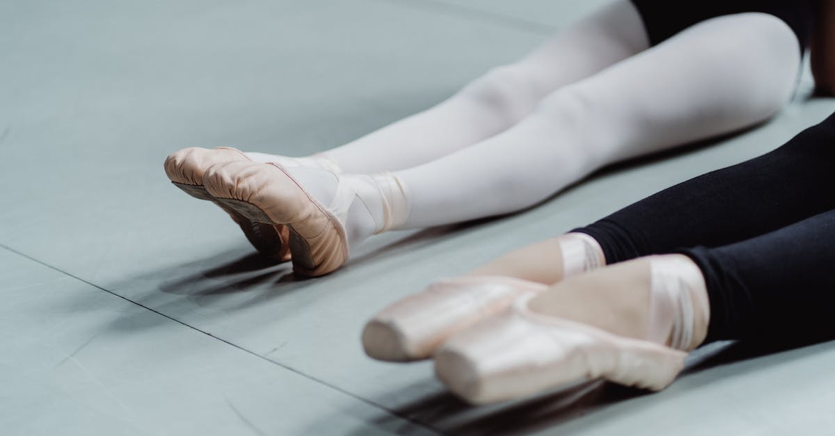 How do I gain skill points from public dungeons? - From above of crop anonymous woman and girl in pointes warming up on floor before ballet training in light studio