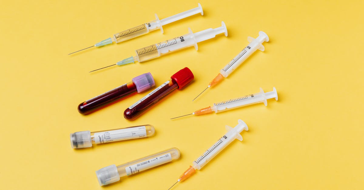 How do I get a blood sample from the Manbat? - From above composition with medical syringes of different sizes arranged with test tubes filled with blood samples placed on yellow surface