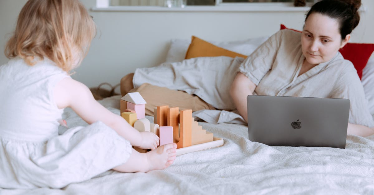 How do I get back a lost PG3D account using Game Center on IOS? - Cute toddler girl playing with wooden blocks on bed while mother using laptop nearby