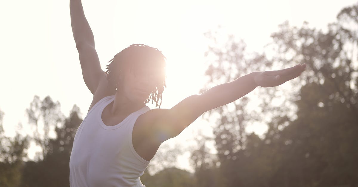 How do I get back from Eve? - Sportsman in undershirt raising arms while doing exercises in sunny day in park