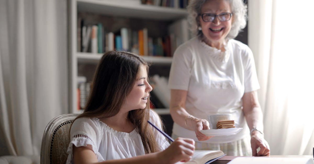How do I get the 7th grandma in cookie clicker - Cheerful grandmother in glasses and casual clothes smiling at camera while giving pastry on plate and mug of tasty beverage to joyful teenager sitting at table with books and exercise book and study in light cozy living room
