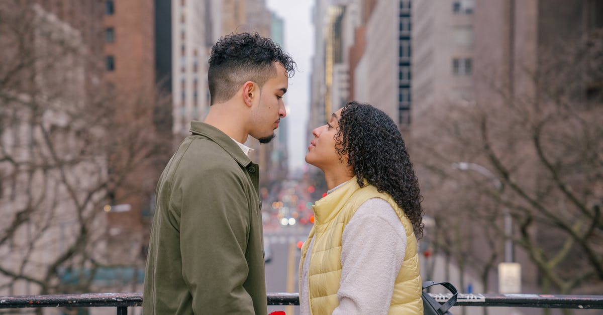 How do I get to the other side of this bridge? - Side view of romantic Hispanic couple in casual clothes looking at each other while standing on bridge near metal fence against city street in daytime How do I get to the other side of this bridge? - Side view of romantic Hispanic couple in casual clothes looking at each other while standing on bridge near metal fence against city street in daytime