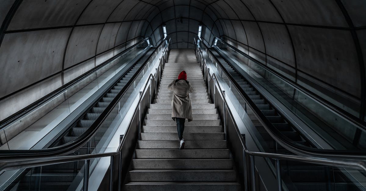 How do I go up staircases? - Person Climbing Staircase Between Escalators