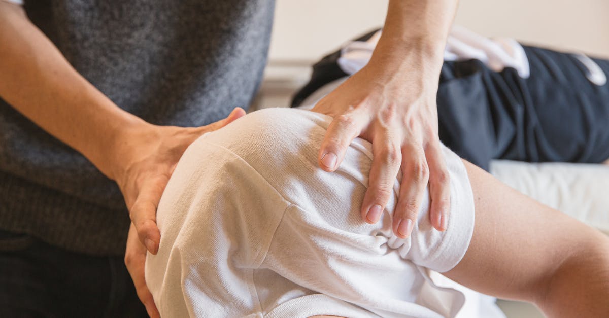 How do I heal land-armies? - Crop anonymous medical specialist rubbing shoulders of male client lying on couch in medical salon