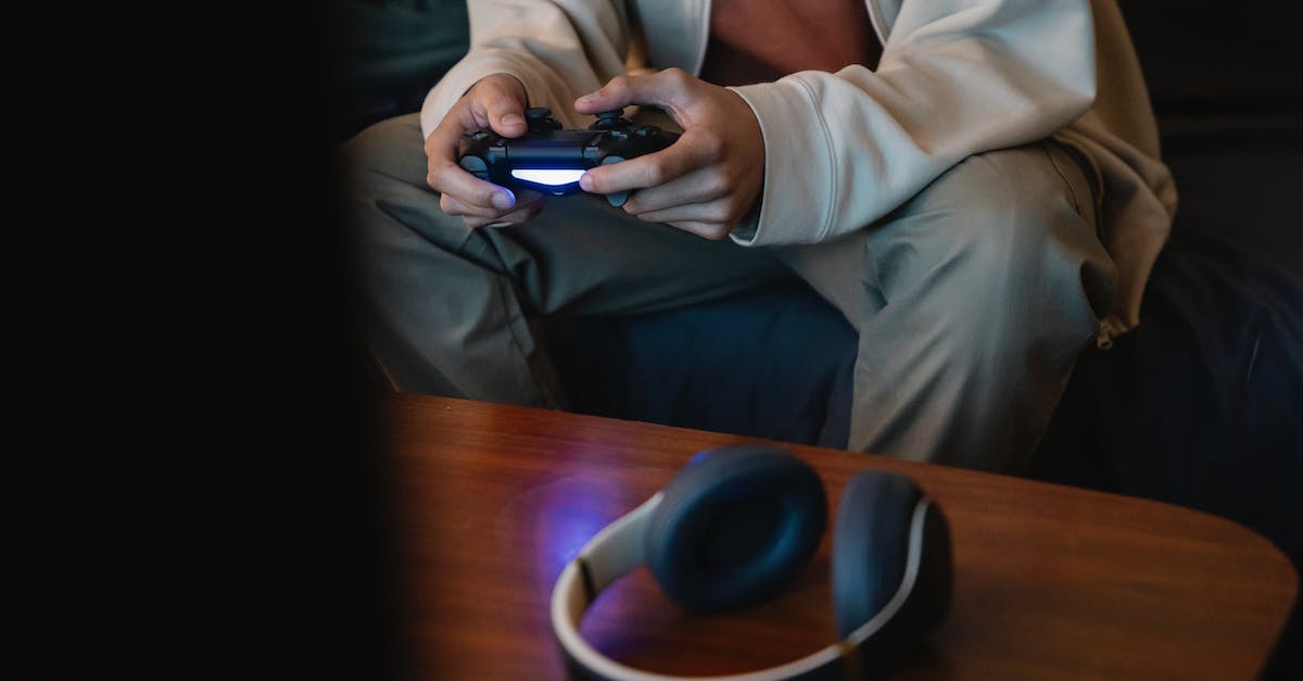 How do I input custom names into my game? - Crop unrecognizable man with joystick playing video game while sitting against table with modern headset in house room