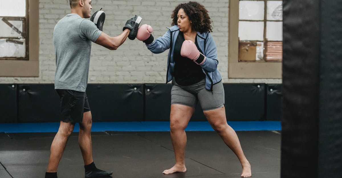 How do I knock over the pins on level W3-4 strike lake? - Ethnic male instructor with focus mitts combating with overweight African American female athlete while practicing boxing in gymnasium