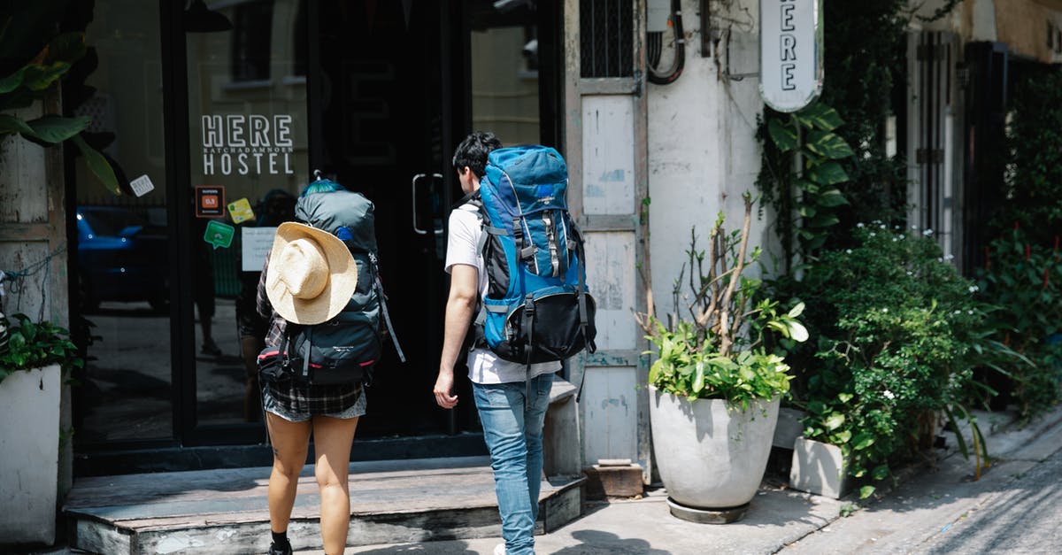 How do I know if my bag is full? - Unrecognizable couple of travellers with backpacks entering hotel How do I know if my bag is full? - Unrecognizable couple of travellers with backpacks entering hotel