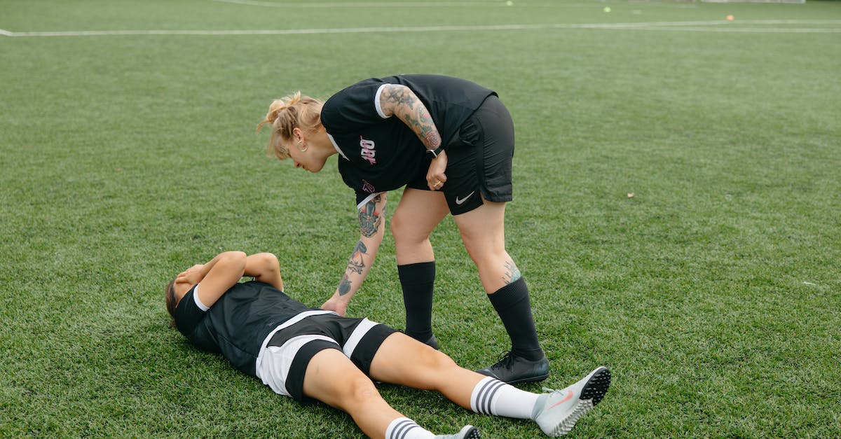 How do I know when to help my teammates? - Woman in Black Shirt and Black Shorts Lying on Green Grass Field