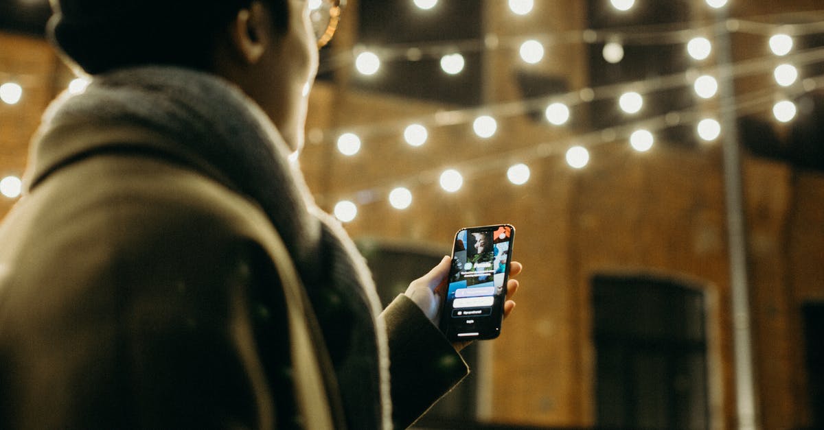 How do I login to my Mojang account on my minecraft app? - Selective Focus Photography of Man Using Smartphone Beside String Lights