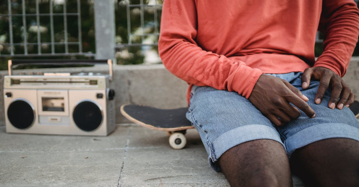 How do i make a button with delayed reactivation time? [duplicate] - Crop anonymous African American man wearing casual clothes sitting on black skateboard near metal railing and listening to music on vintage cassette recorder