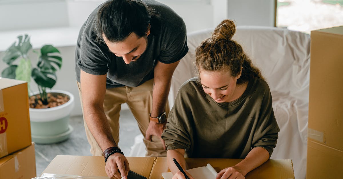 How do I make house appear in the happy home show case because it was empty? - Cheerful diverse couple writing in notebook near boxes before relocation
