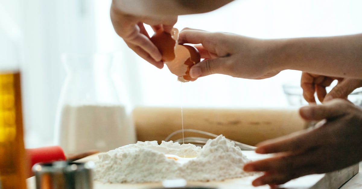 How do I make my friend Notable? - Crop young lady breaking eggs in flour for dough How do I make my friend Notable? - Crop young lady breaking eggs in flour for dough