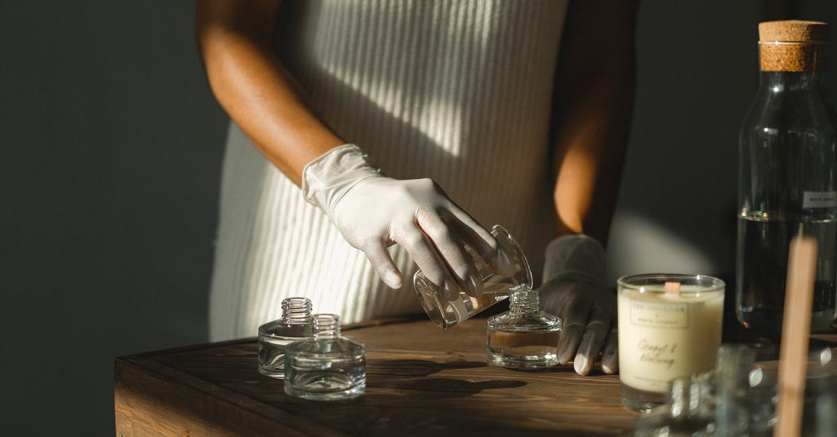 How do I make myself less fascinating? - Unrecognizable crop African American female pouring essential oil in glass bottle while making liquid incense at table