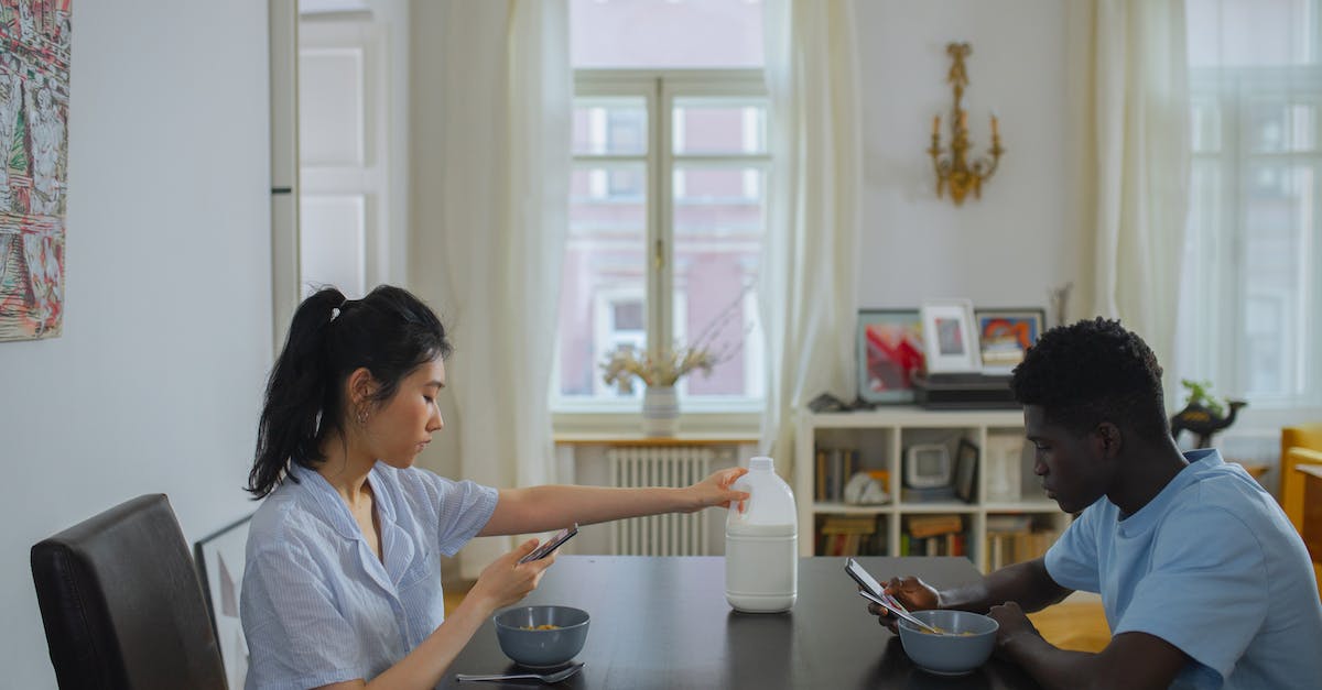 How do I milk a cow? - Woman in White Shirt Sitting Beside Man in White Shirt