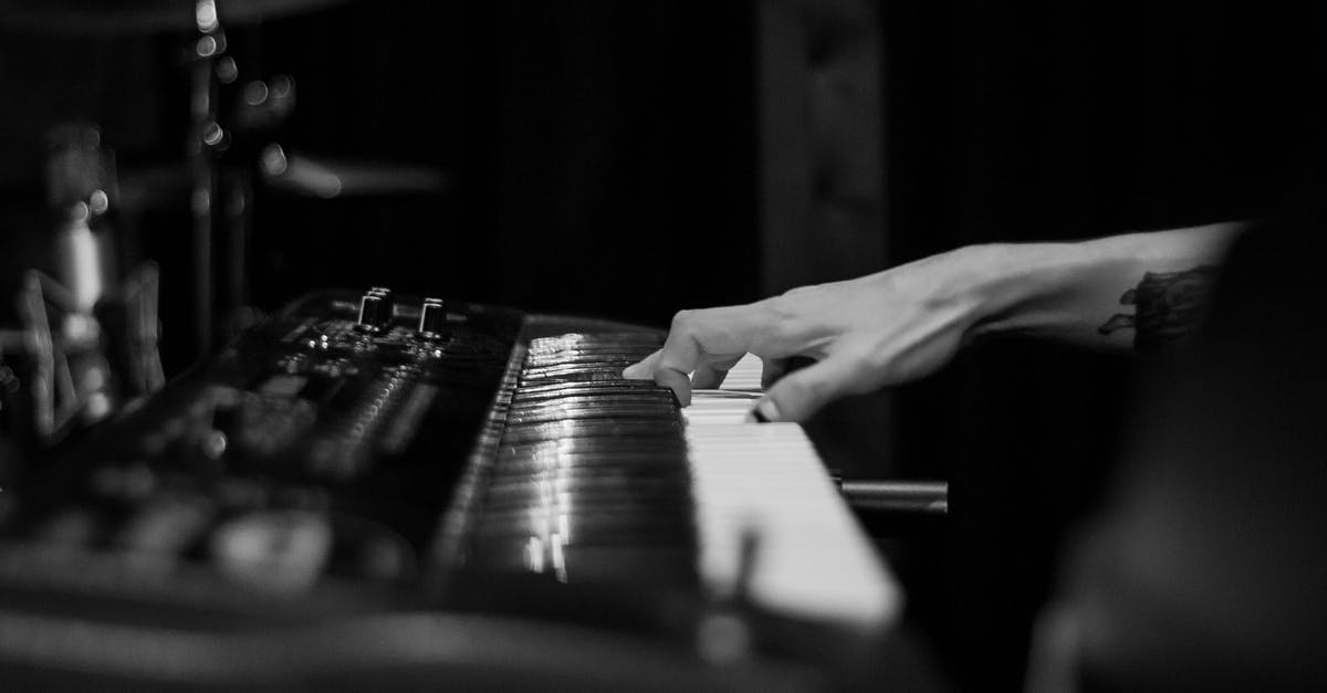 How do I perform something like rolling the controller shock button on keyboard properly? - Black and white of crop anonymous tattooed musician playing chord on synthesizer with sound board
