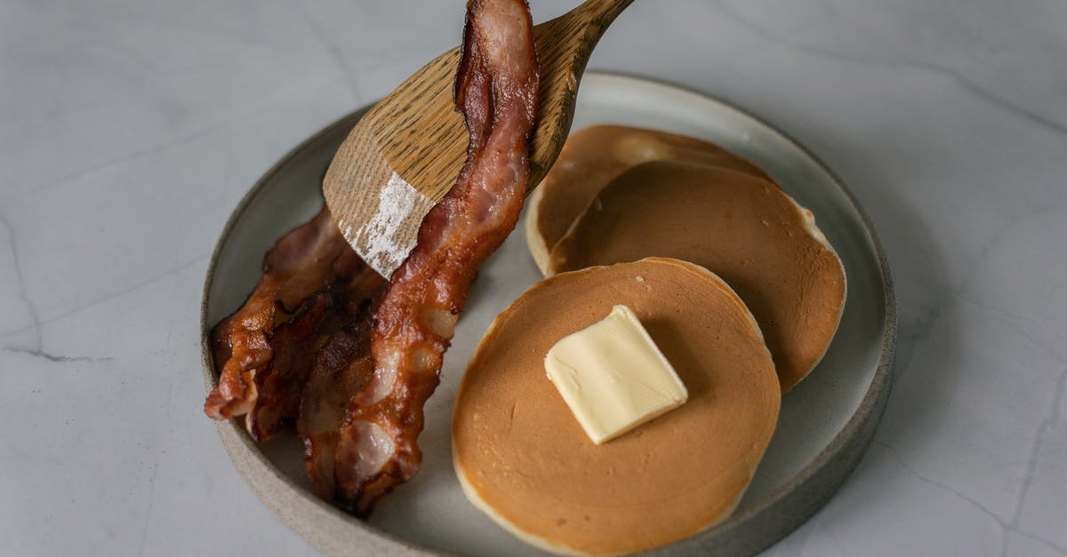 How do I place a specific piece of furniture? - High angle of delicious pancakes with butter piece near sliced fried bacon and wooden kitchen spatula on plate on white table in bright place How do I place a specific piece of furniture? - High angle of delicious pancakes with butter piece near sliced fried bacon and wooden kitchen spatula on plate on white table in bright place