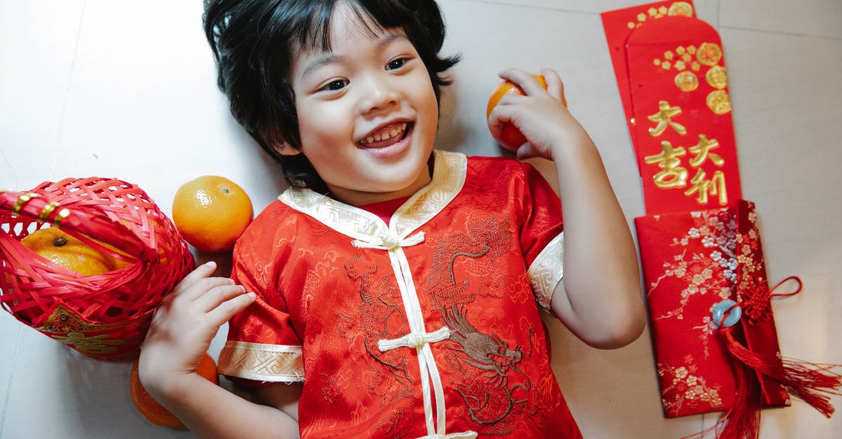 How do I play Minecraft Pocket Edition with my niece on LAN? [duplicate] - Top view of cheerful ethnic child with fresh oranges and red packets looking up while lying on floor during New Year holiday