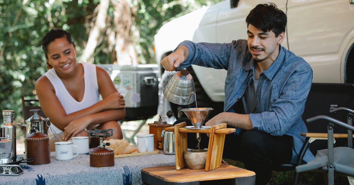 How do I prepare for summer heat? - Happy diverse couple preparing pour over coffee in campsite