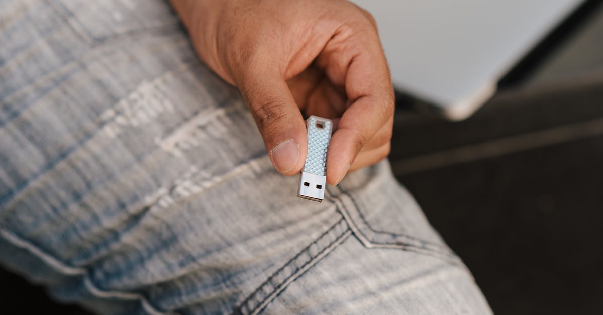 How do I preserve my save data - From above of crop anonymous male in jeans demonstrating flash drive while sitting near laptop