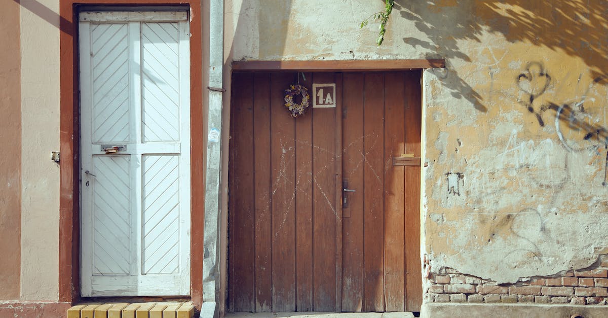 How do I proceed past this location with an eye and a blocked door? - Exterior of weathered brick residential building with shabby wooden doors on sunny day How do I proceed past this location with an eye and a blocked door? - Exterior of weathered brick residential building with shabby wooden doors on sunny day