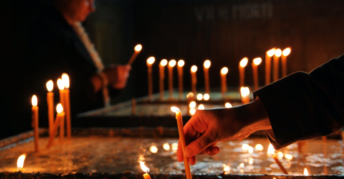 How do I put out the fire of the second chest? - Crop person putting candle in church