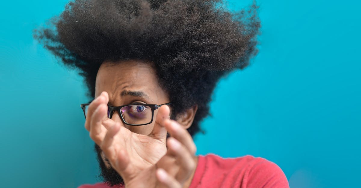 How do I question a witness with emotions instead of evidence? - Scared young ethnic man looking through hands on blue background in studio
