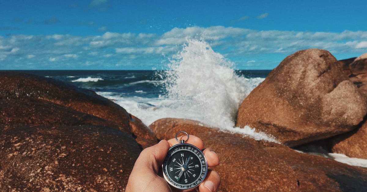 How do I reach a barrel stuck on a cliff? - Crop anonymous male tourist with compass in hand standing on massive stony shore washed by splashing waves How do I reach a barrel stuck on a cliff? - Crop anonymous male tourist with compass in hand standing on massive stony shore washed by splashing waves
