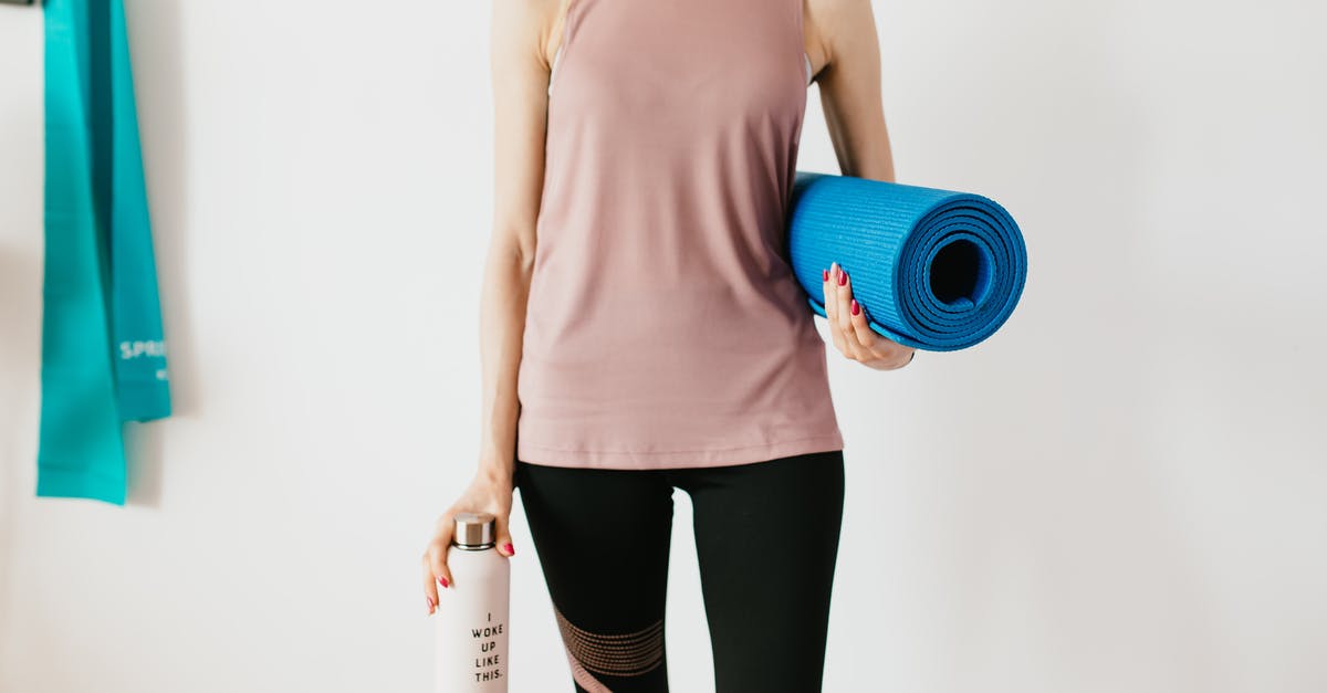 How do I reach the center of Daiba Studio's Back Alley? - Faceless slim female athlete in sportswear standing with blue fitness mat and water bottle while preparing for indoors workout How do I reach the center of Daiba Studio's Back Alley? - Faceless slim female athlete in sportswear standing with blue fitness mat and water bottle while preparing for indoors workout