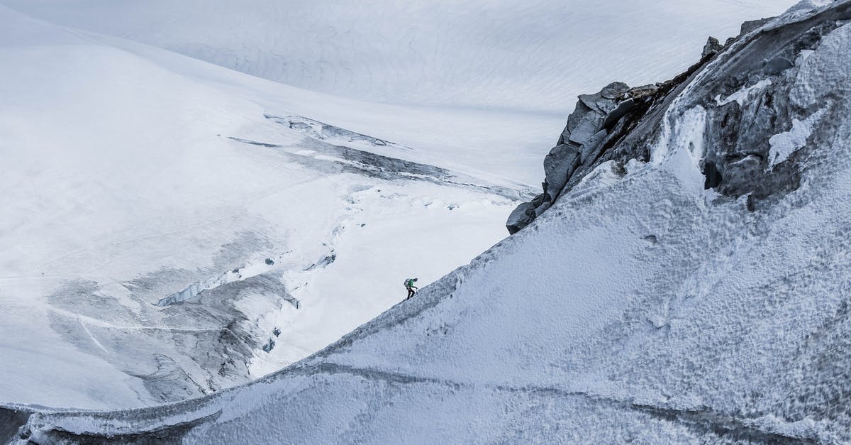 How do I retreat from an expedition with all my resources in Loop Hero? - From above distant alpinist on snowy rough mountain slope against frozen spacious mountainous valley in daylight