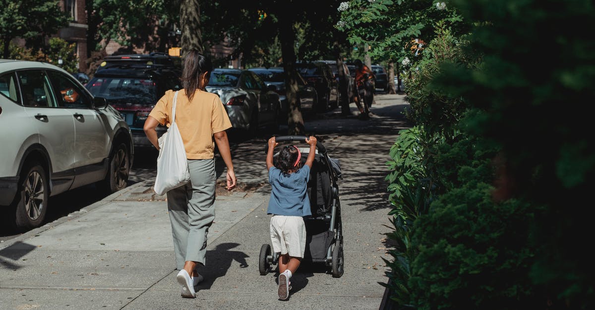 How do I roll back versions? - Full body back view of anonymous ethnic woman with bag walking on sidewalk near girl pushing baby stroller on sunny street How do I roll back versions? - Full body back view of anonymous ethnic woman with bag walking on sidewalk near girl pushing baby stroller on sunny street