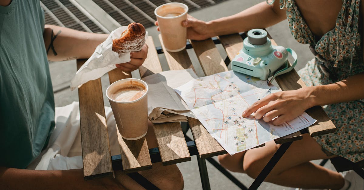 How do I search photos by player ID? - From above of crop anonymous couple searching route in map while having coffee and croissant