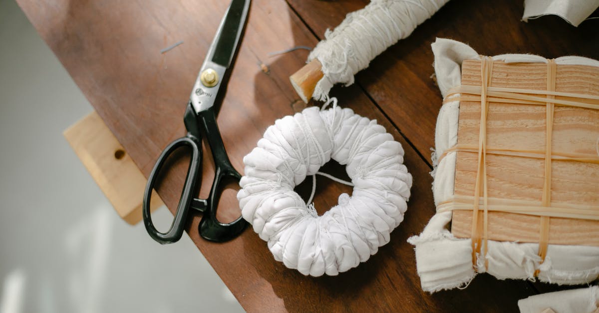 How do I set a /kill command on a block? - Top view of scissors against coil of twine and textiles with wooden block tied with threads on desk