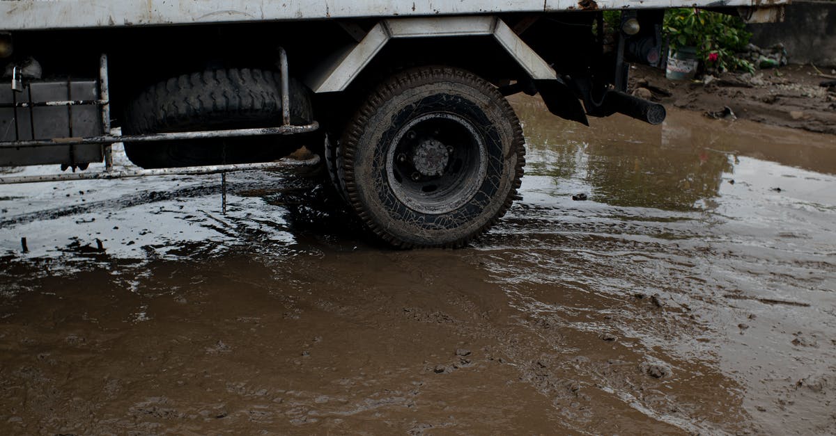 How do I spare Undyne? - Old transport with rusty surface on roadway with rippled puddle and mud in daylight
