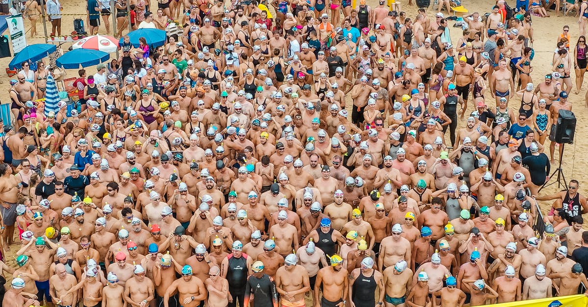 How do I start the crossbow challenge? - From above people in swimsuits standing together behind line tape ready to start swim marathon on seashore