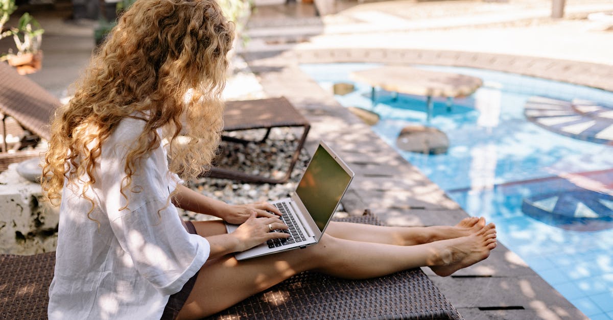 How do i testfor a player using a water bucket with scoreboards? - From above side view of unrecognizable barefoot female traveler with curly hair typing on netbook while resting on sunbed near swimming pool on sunny day