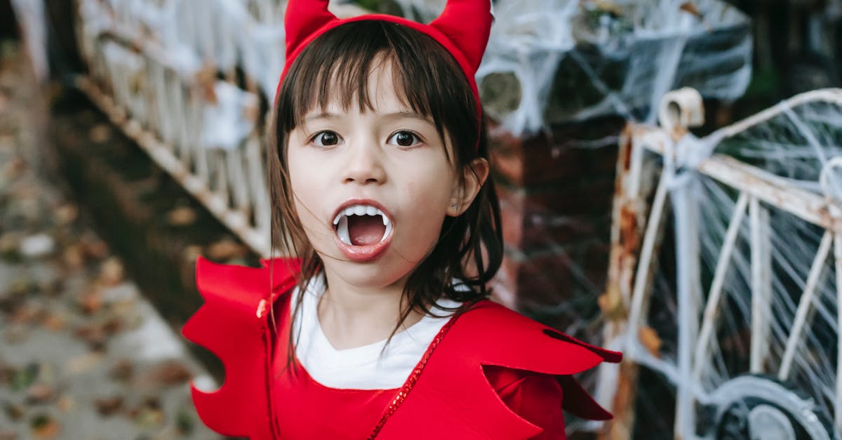 How do I trick the devil? - Little girl standing in street in devil costume at Halloween How do I trick the devil? - Little girl standing in street in devil costume at Halloween