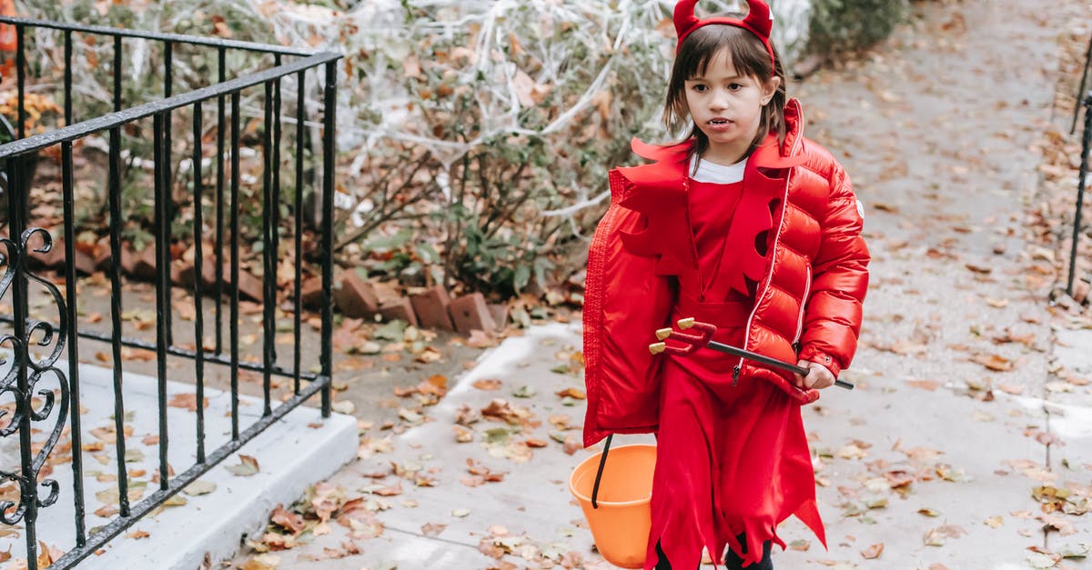 How do I trick the devil? - Little girl in red costume of devil for Halloween with horns and pitchfork walking on street in daytime in autumn How do I trick the devil? - Little girl in red costume of devil for Halloween with horns and pitchfork walking on street in daytime in autumn