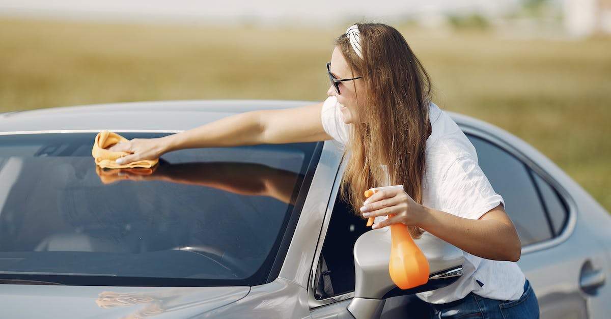 How do I use White soapstone? - Side view of cheerful female driver in sunglasses and casual clothes cleaning windshield of modern car with microfiber cloth and spray bottle against green field