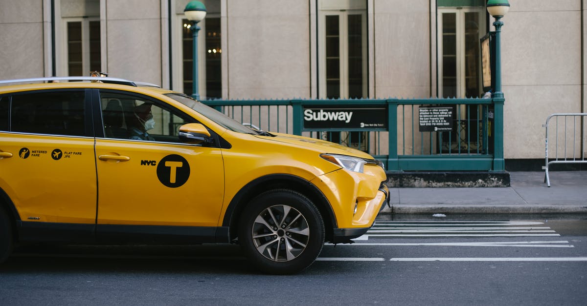 How do I warp to a safe-spot in wait mode? - Contemporary yellow taxi with driver in medical mask standing on empty road near modern building and subway station entrance during coronavirus pandemic in New York USA