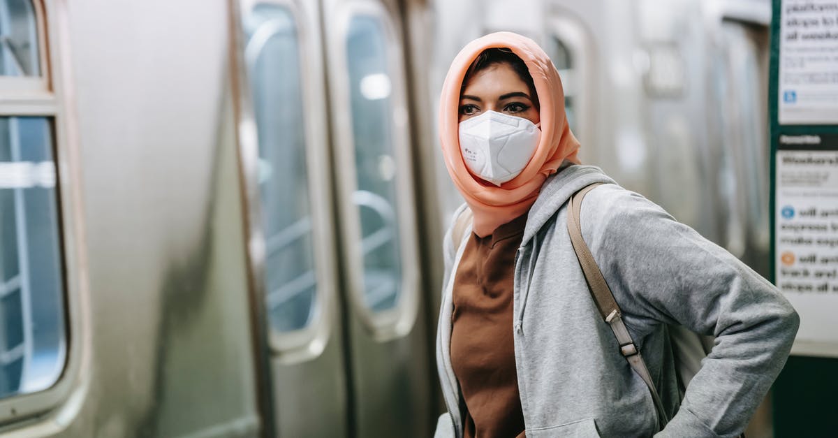 How do I warp to a safe-spot in wait mode? - Young Muslim female in casual wear and traditional headscarf with protective mask on subway platform