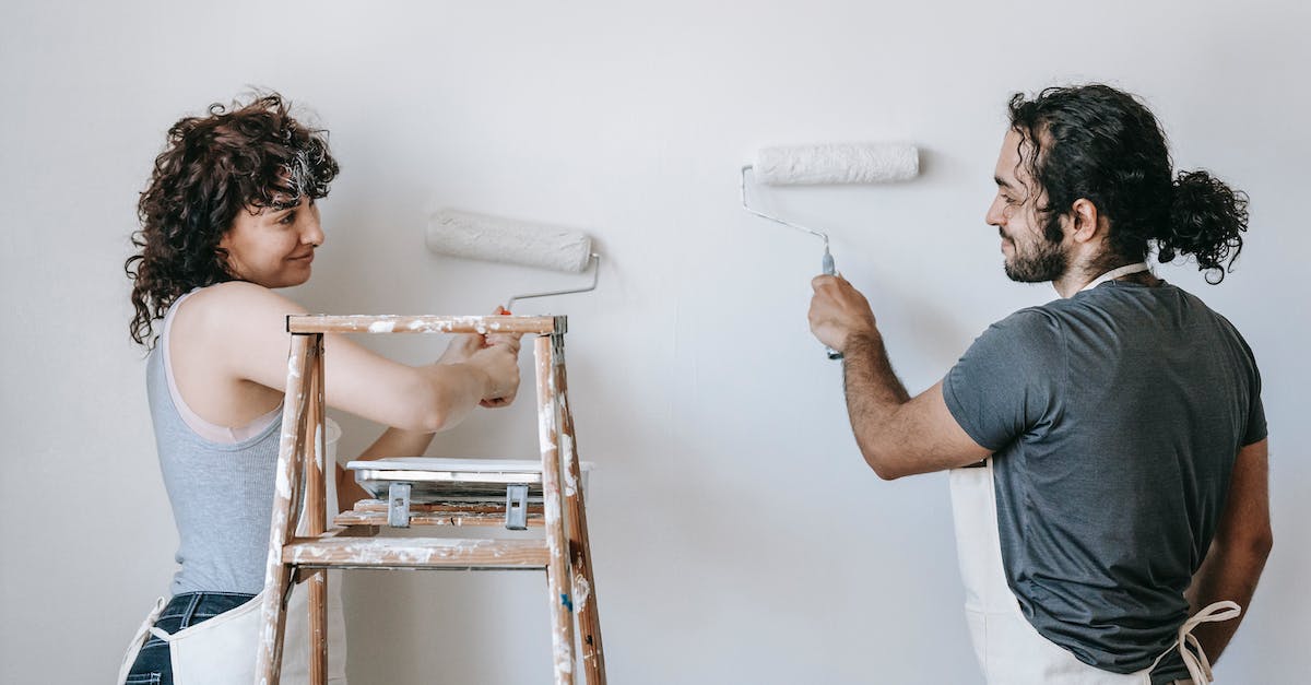How do similar procs interact? - Smiling ethnic couple painting wall with roller brushes at home