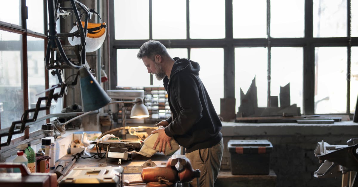 How do teleporters work in Steamworld Dig? - Side view of male workshop owner standing near messy workbench and fixing metal details while using instruments during work How do teleporters work in Steamworld Dig? - Side view of male workshop owner standing near messy workbench and fixing metal details while using instruments during work