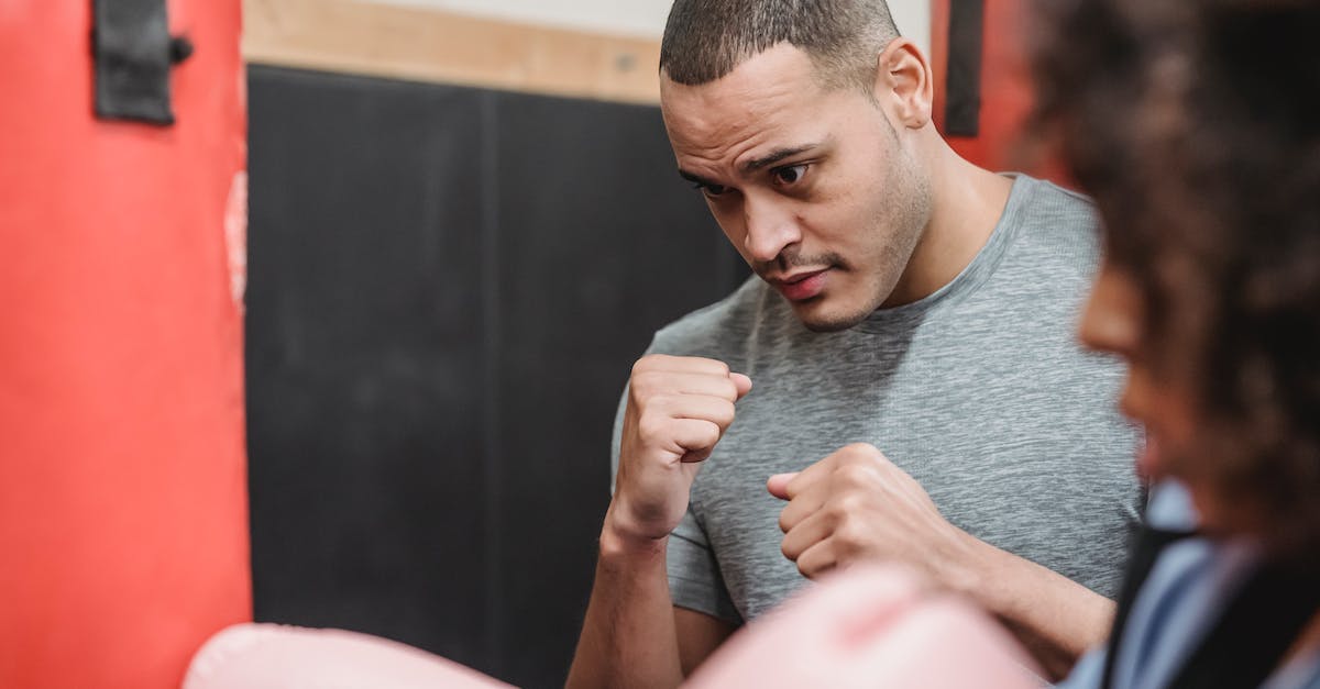 How do the specific bullet paths and hit boxes work? - Focused ethnic personal trainer with fists training with crop female hitting punching bag during boxing workout