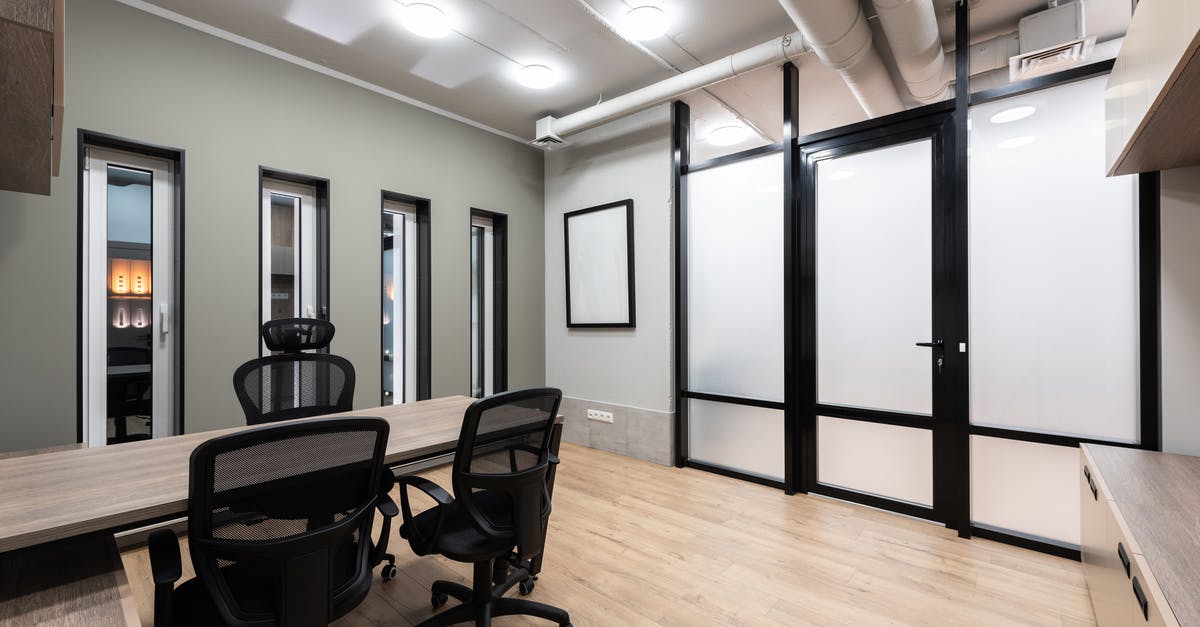 How do these 'door blockers' work, and is there an equivalent in real life? - Wooden table and black office chairs placed in spacious room in new contemporary workplace